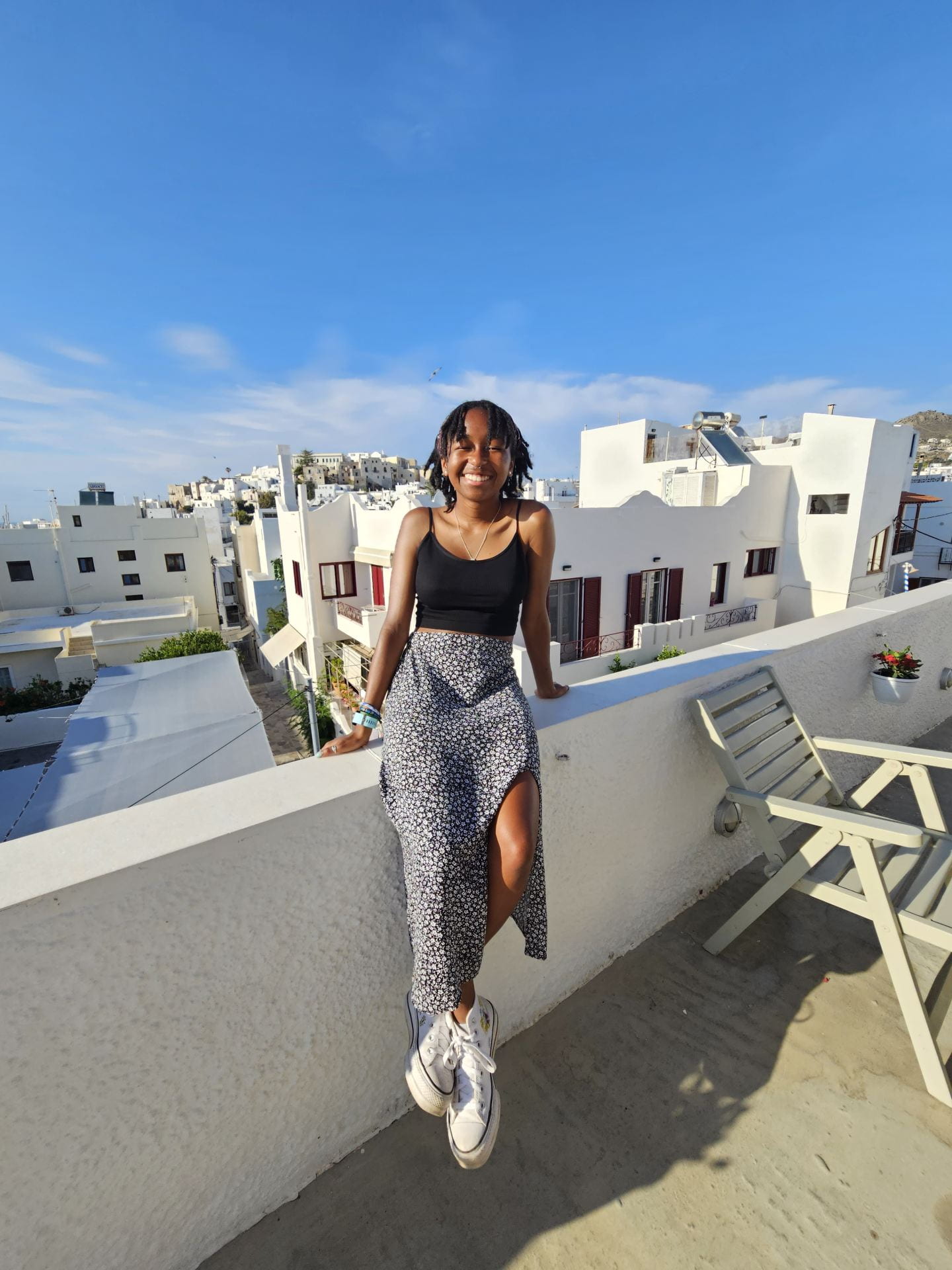 smiling young woman standing on a balcony on an island in Greece